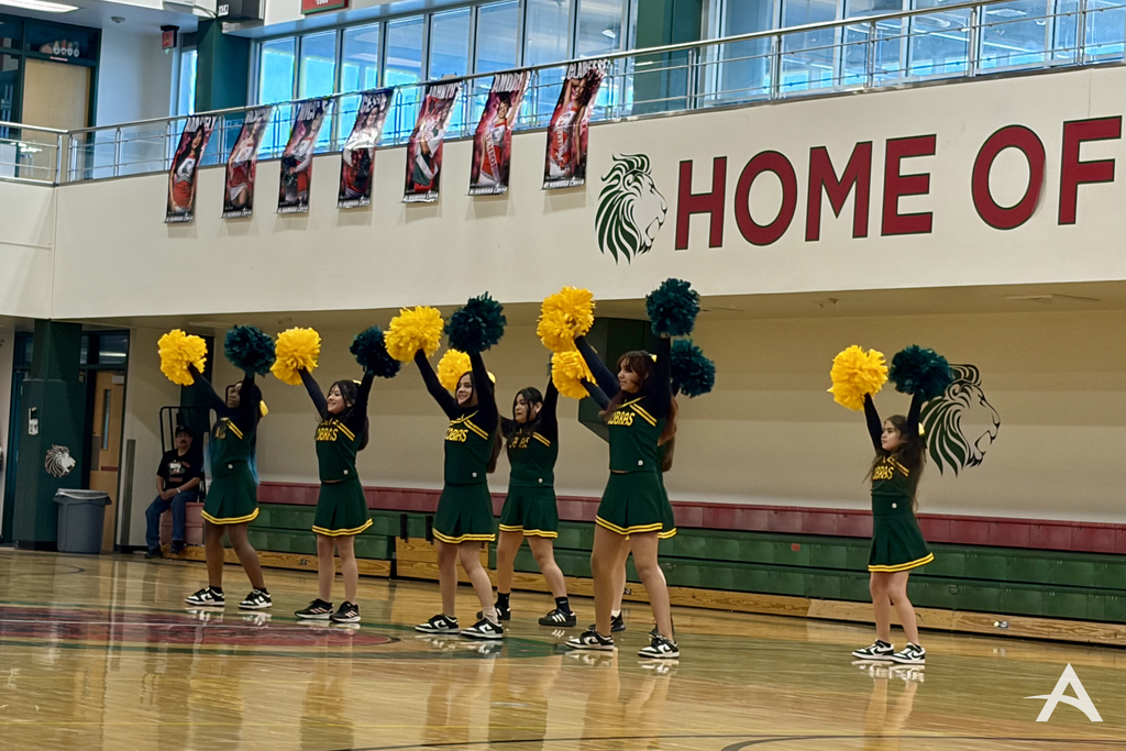Group students in cheer competition with their hands up in the middle of their routine.