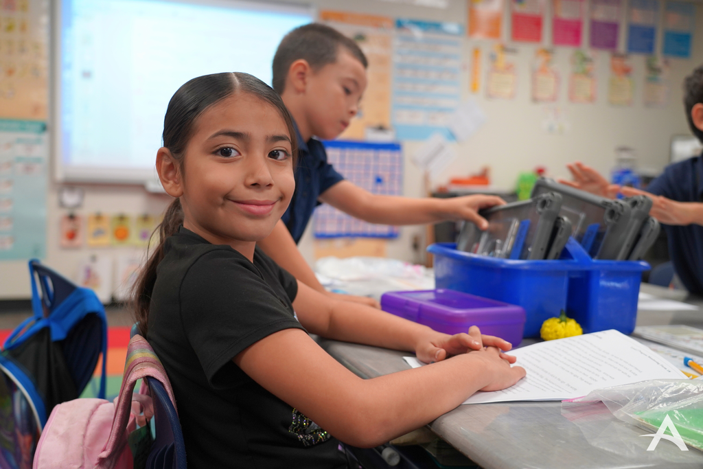Student sitting on a desk looking at the camera smiling