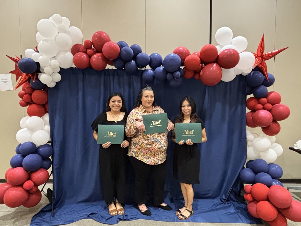 Three women stand under a balloon arch in front of a blue backdrop, each holding a green certificate.