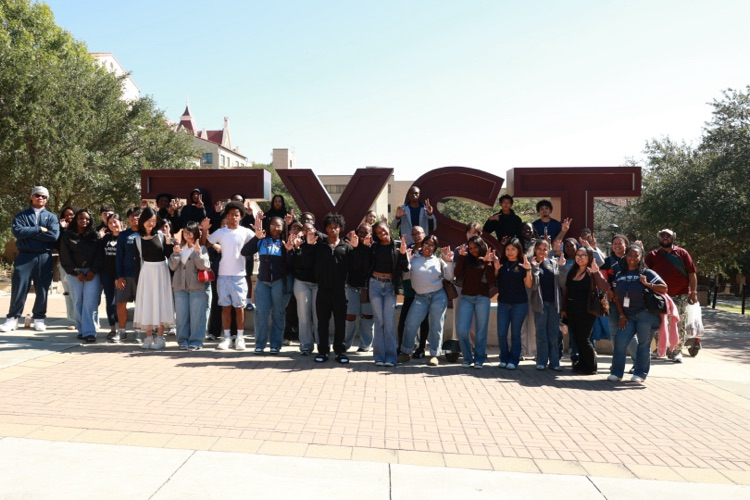 Group of students standing in front of large letters spelling out "TVST" on a paved area.