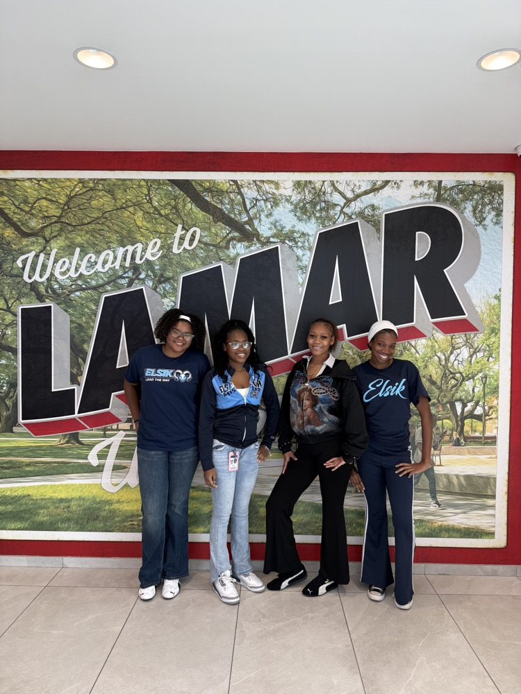 Five students stand next to each other in front of a large mural of trees and a grassy area.