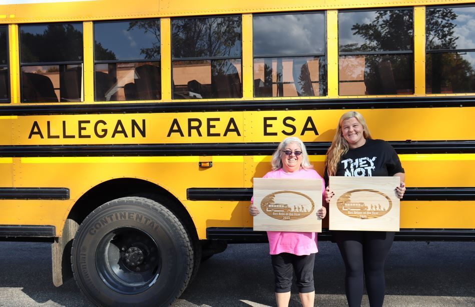 Carol and Chelsy hold award in front of school bus