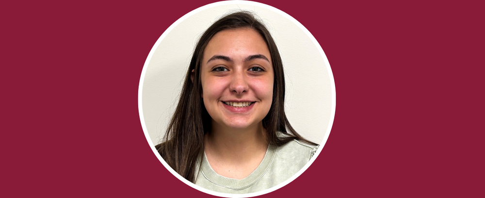 Lexie Davis smiles at the camera with a maroon background.