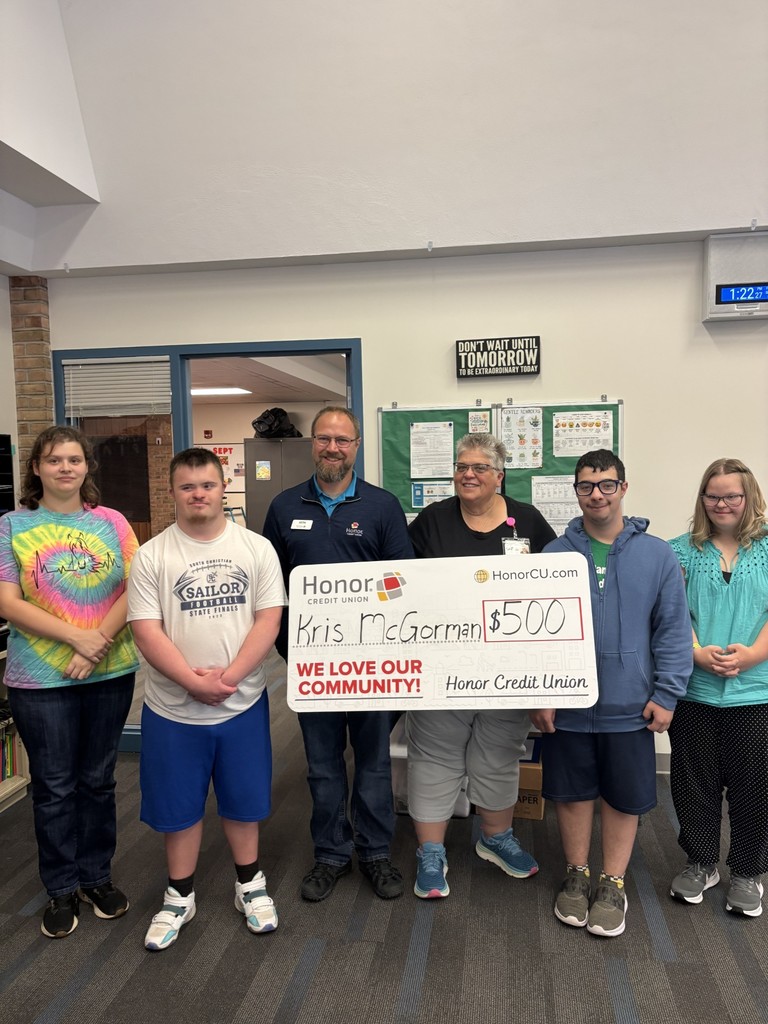 Kris McGorman holding check from Honor Credit Union with 4 students