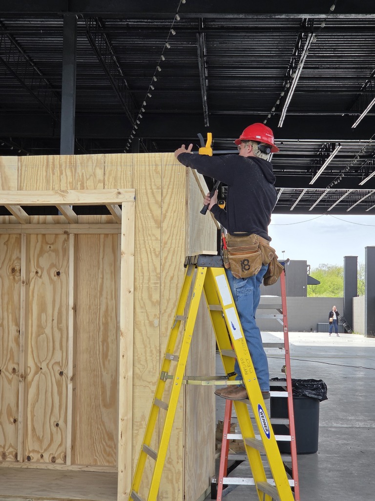 student on a ladder working on the roof of the shed