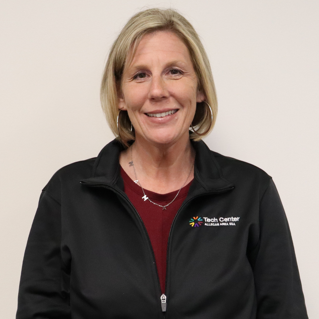 Kim Bruwer, Principal of the Allegan Area ESA Tech Center, smiling in a professional headshot while wearing a black Tech Center Allegan Area ESA jacket and maroon shirt against a light background.