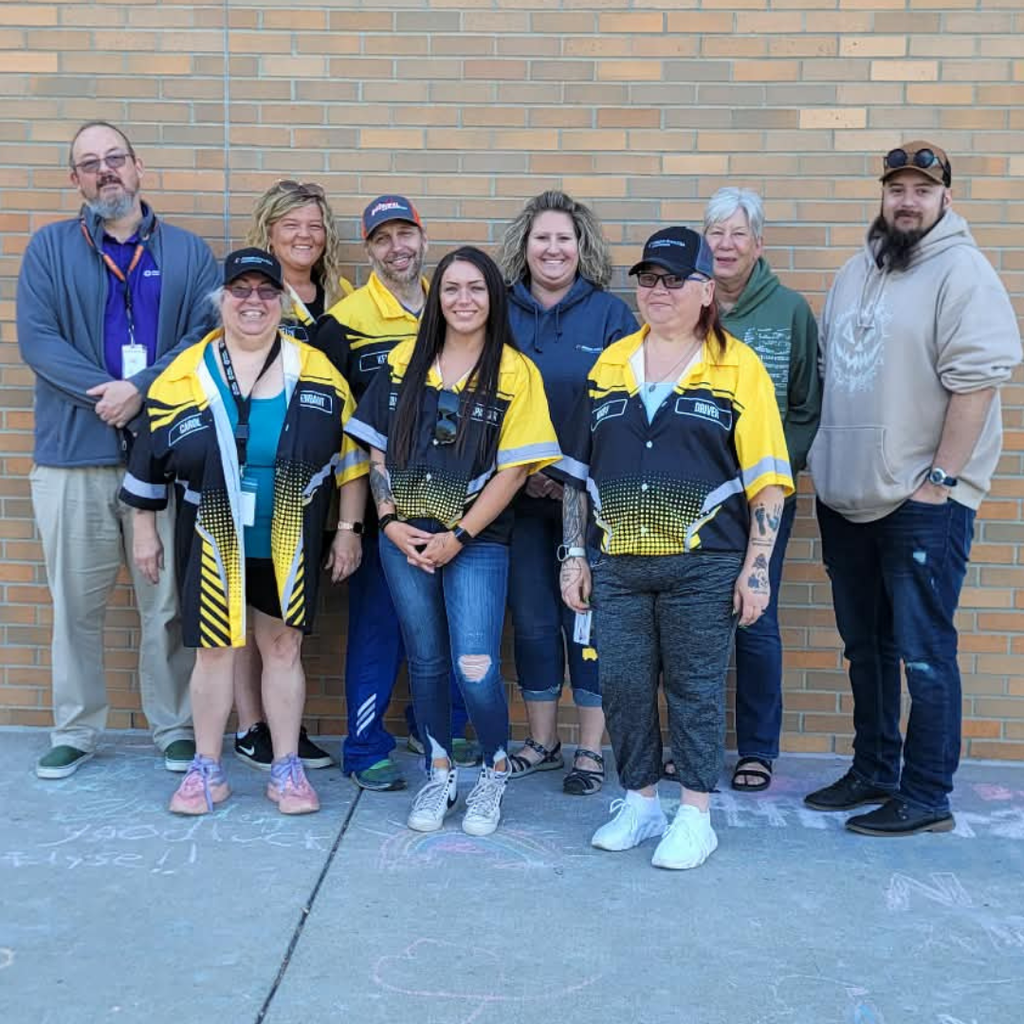 Team members from the transportation department smile at the camera posed against a brick wall.