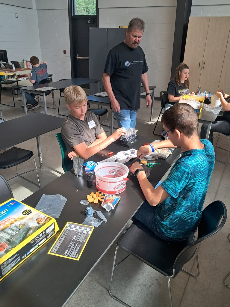 Instructor, Greg Sagodic, walks around the room assisting students on their small engine models.