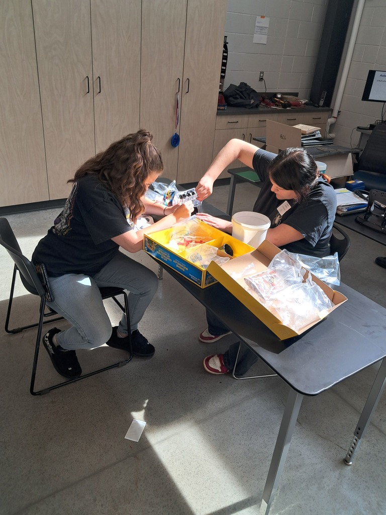 Two female students work together on assembling their small engines.