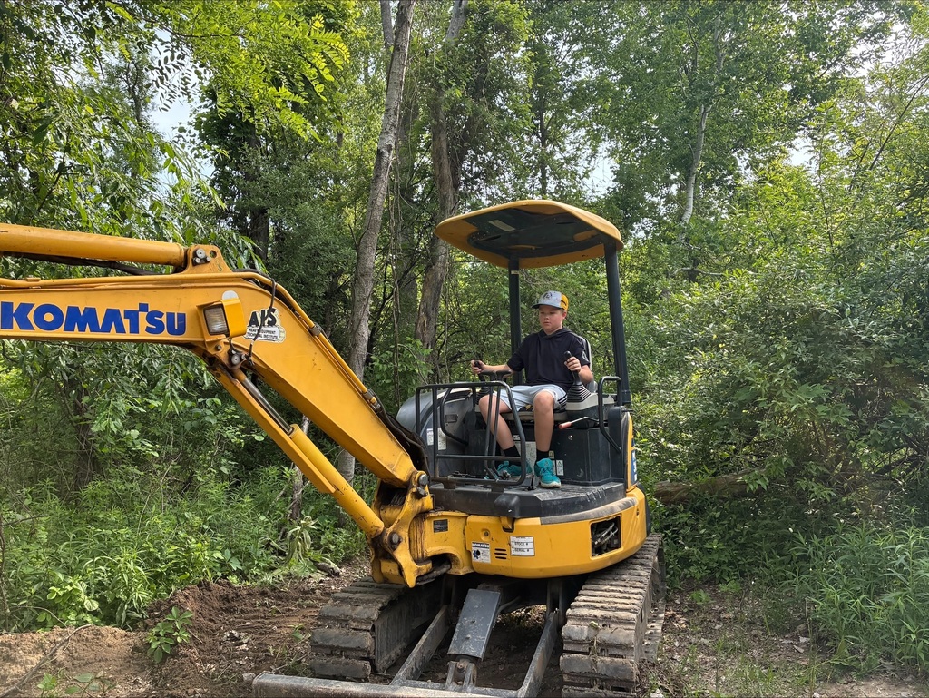 Camper on a yellow Komatsu excavator digging a hole.