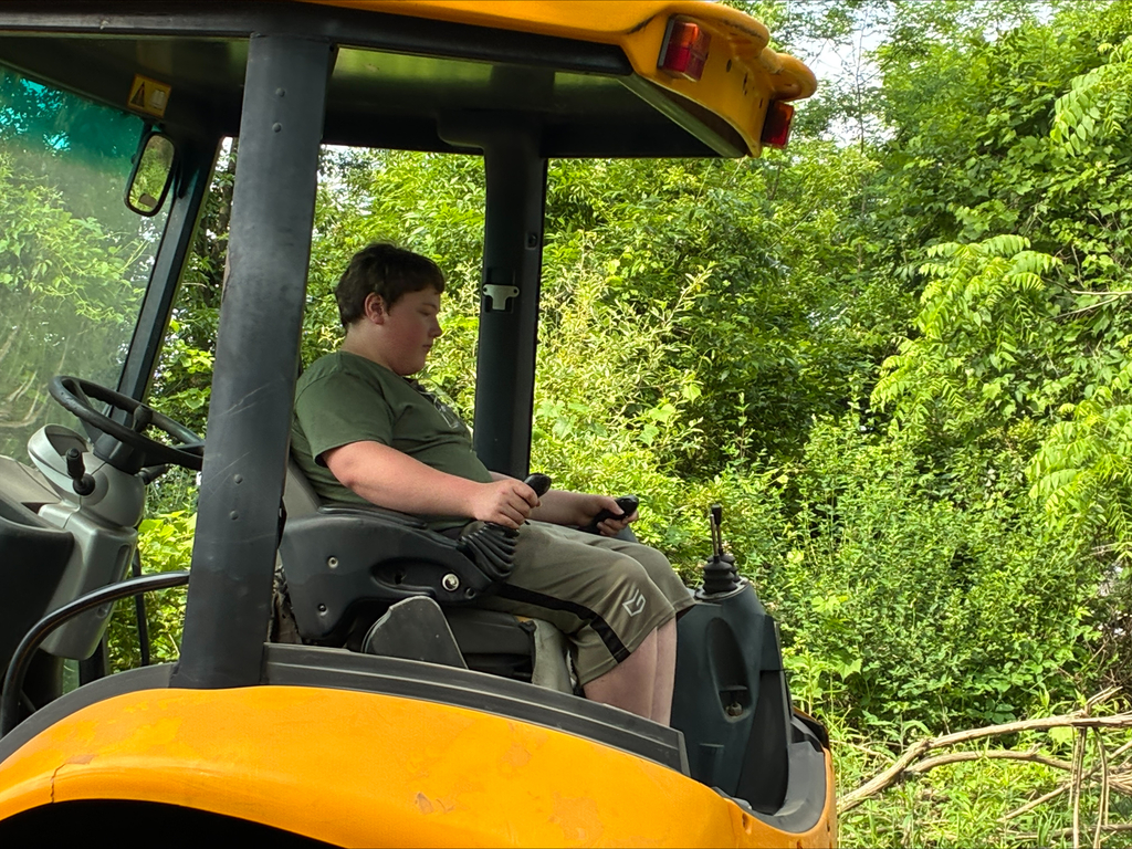 Camper on a yellow JCB excavator digging a hole.