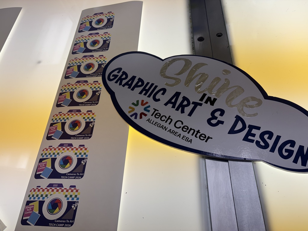 Stickers on a light table of colorful cameras and a sign that says Shine in Graphic Art & Design.