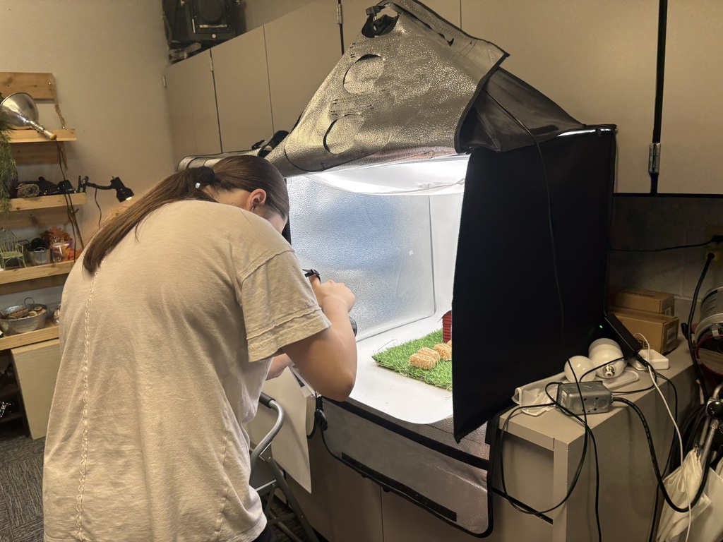 A student taking photos of something inside a photo box.