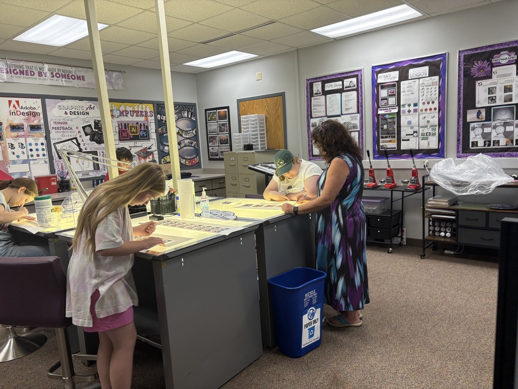 Graphic Art & Design instructor helping students at the light table cutting stickers