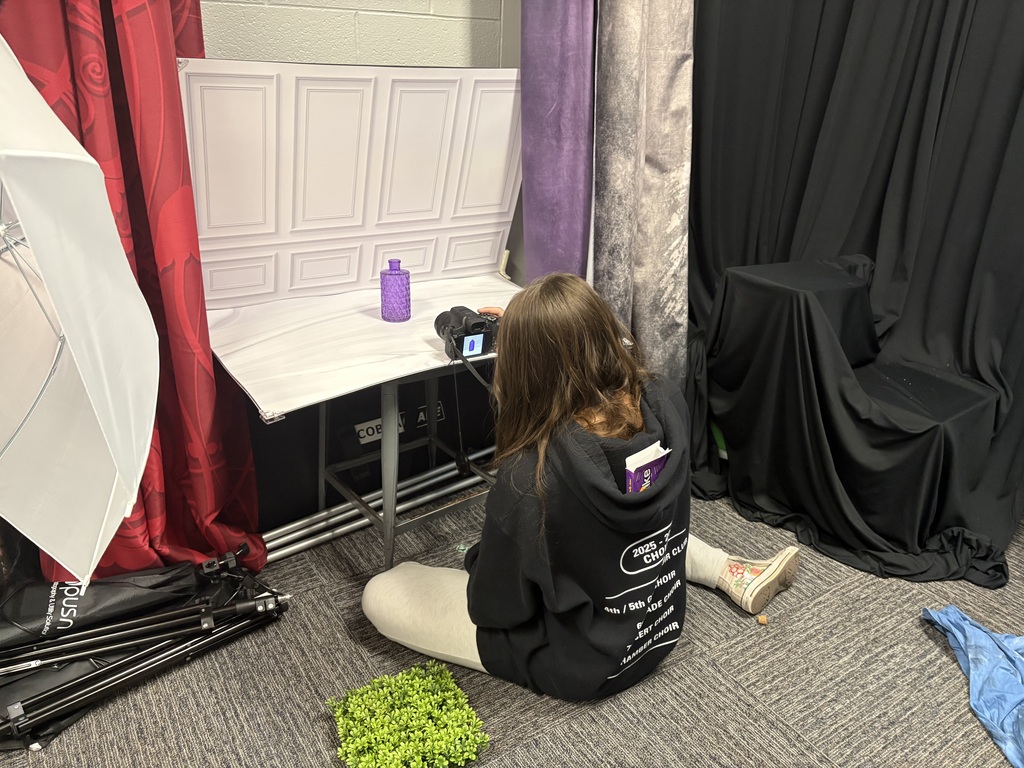 A student taking photos of a purple vase in the photo lab