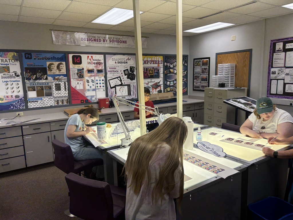 A group of four students cutting out stickers on the light table