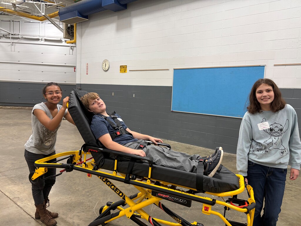2 female campers learning the stretcher utilizing a male camper as the patient.