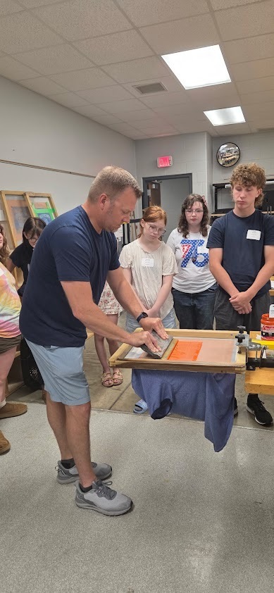 Instructor, Tim Herremans, shows the class how to pull the ink onto their shirts