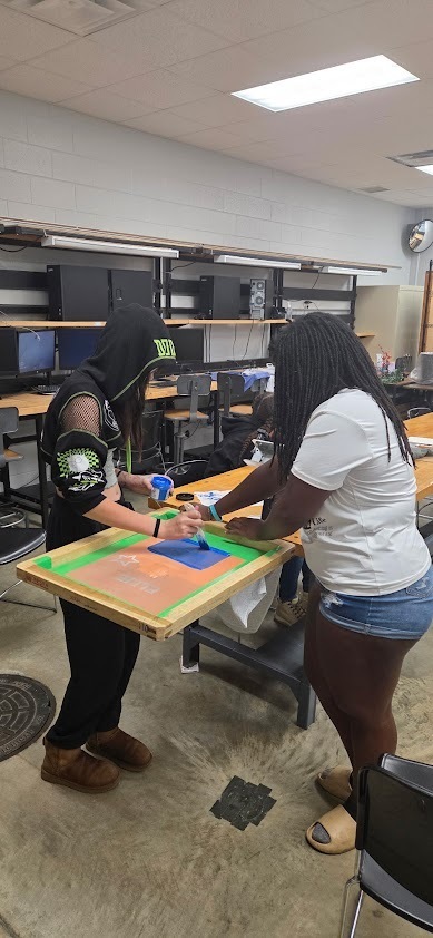 Two students paint ink onto their template