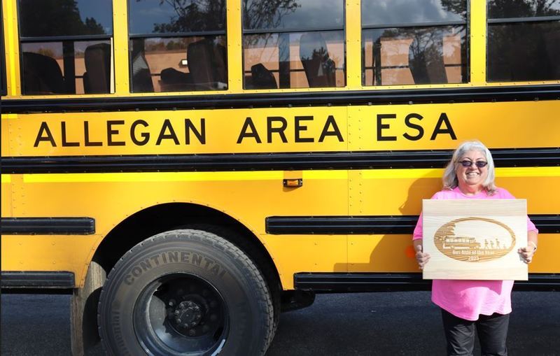Carol Rambo poses in front of bus with award