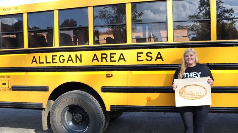 Chelsy Millner holds award in front of bus