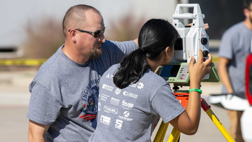 AHS student looks through a transet during Engineering Day with expert helping