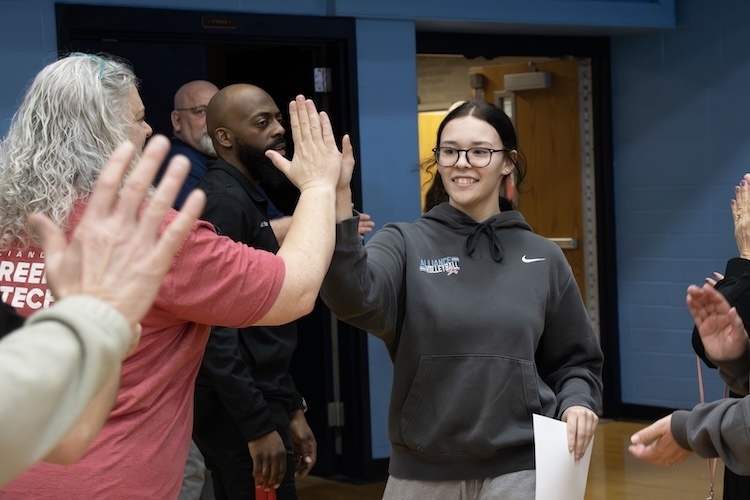 Student walking into the gym, high fiving teachers