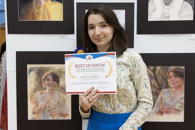 Student standing next to her artwork at last year's Art Show
