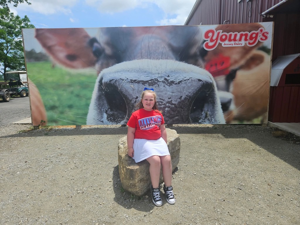 Rosaleigh in front of a mural of a cow at Young's dairy