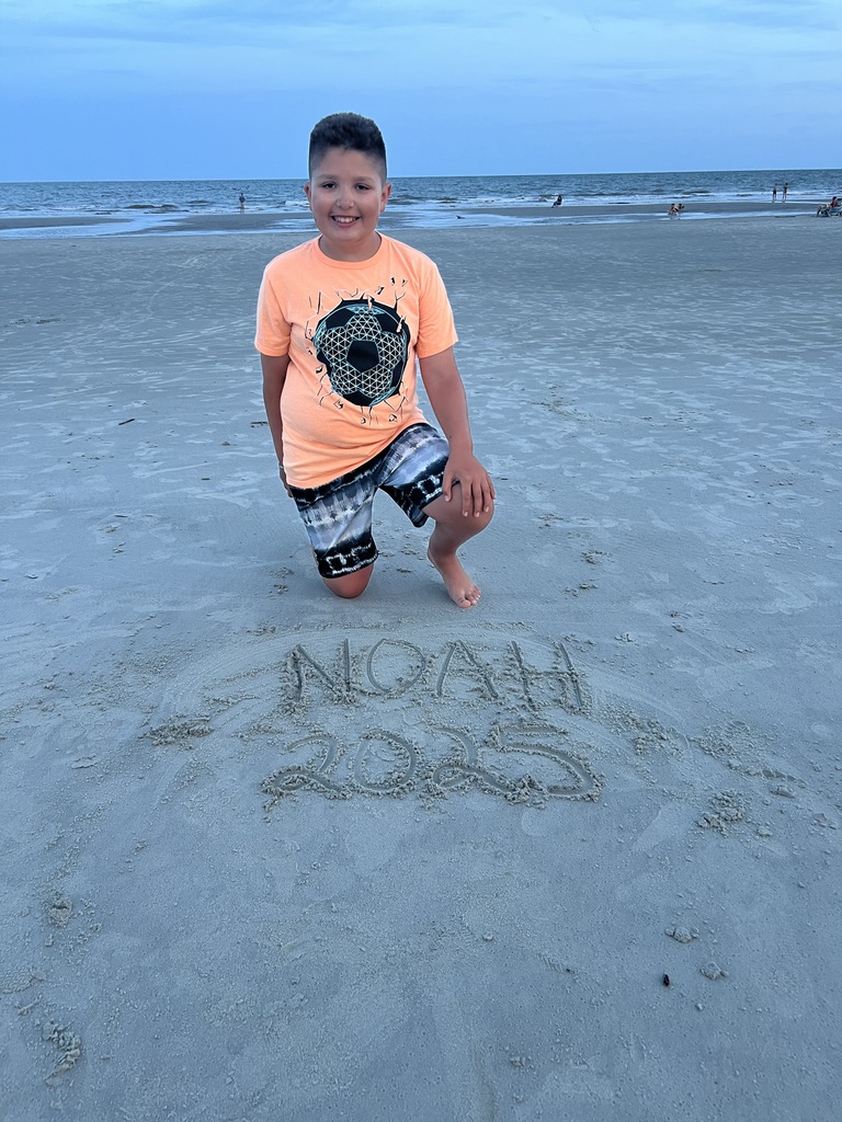 Noah smiling by writing in the sand that says "Noah 2025"