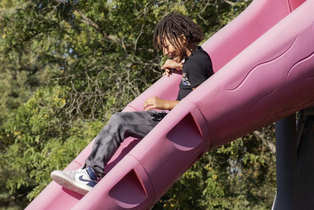 a student smiling while going down a slide