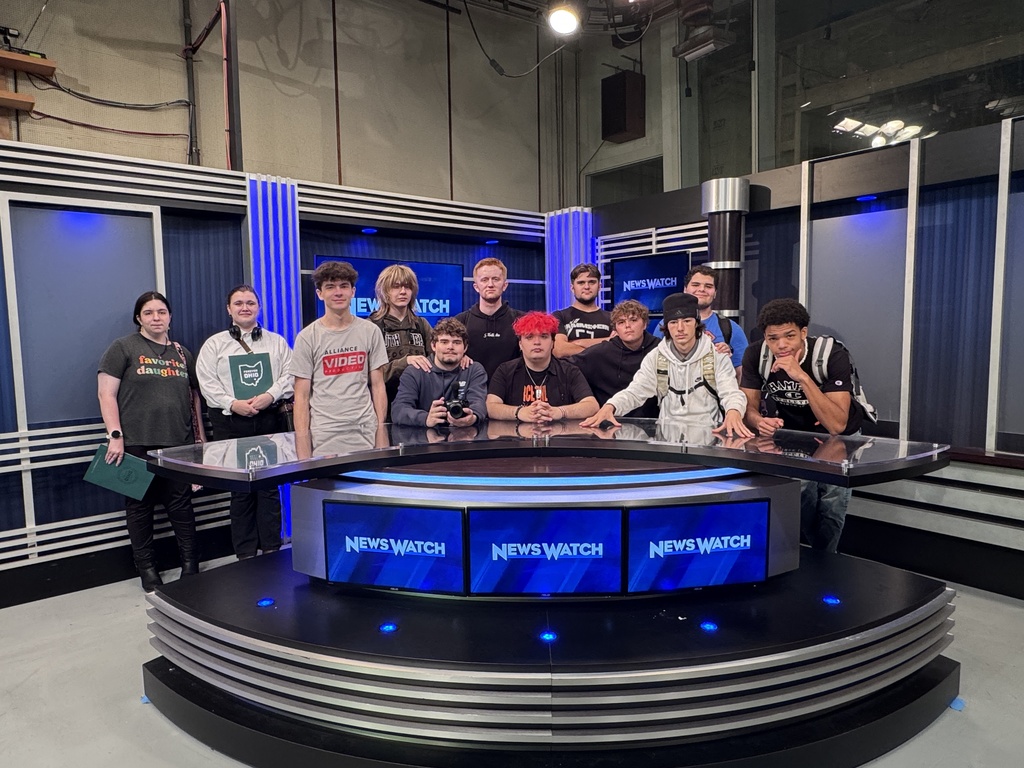 students getting a group picture at the news desk in the studio