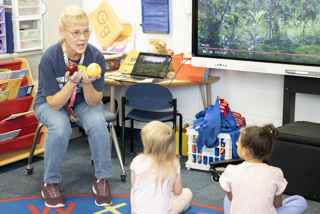 Cindy Gaines holding up the three different apples the student tried in class