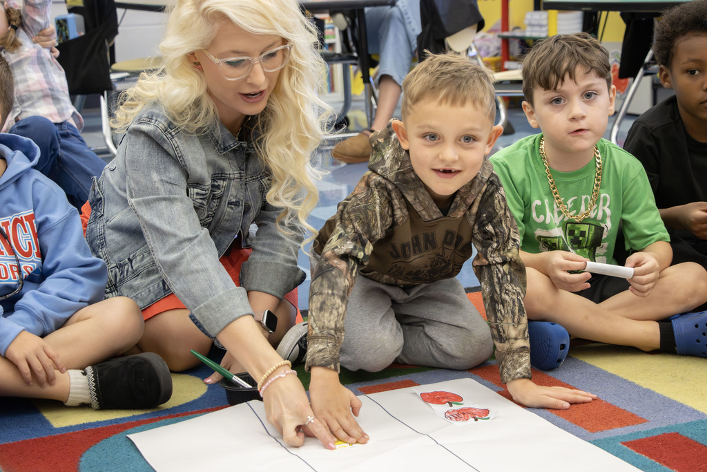 a student gluing a yellow apple on a chart to indicate it was his favorite