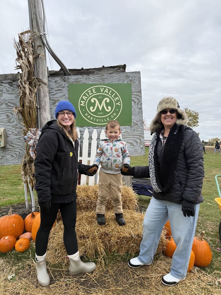 a student with two staff members in front of the Maize Valley sign