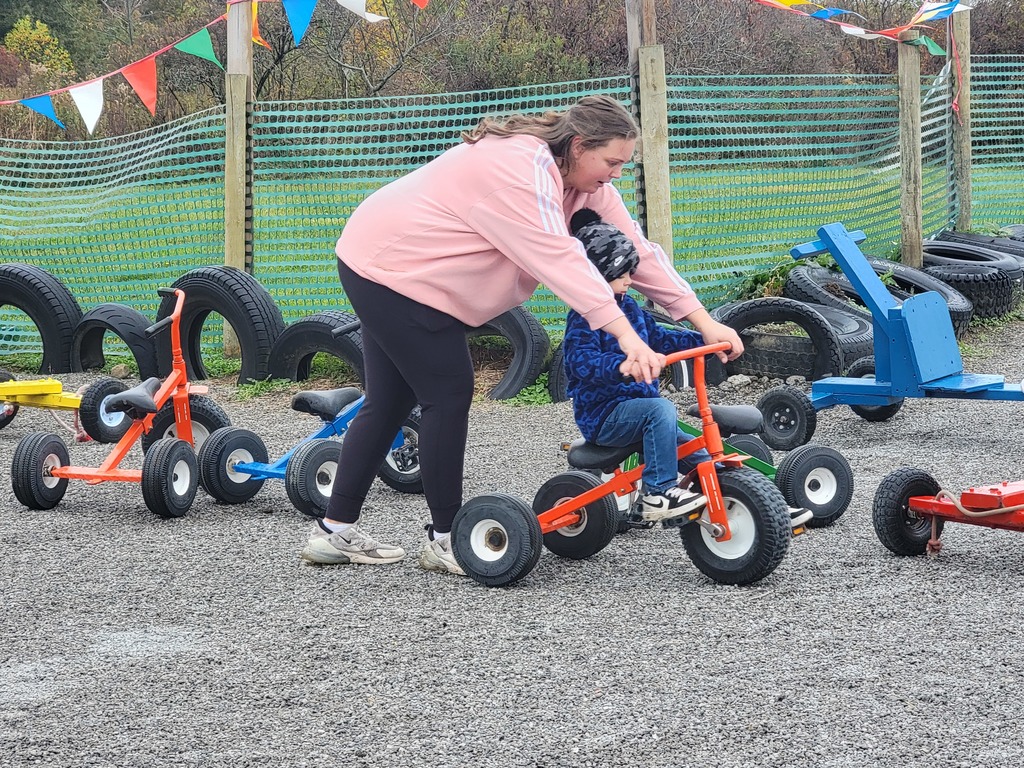 a parent helping her child ride a tricycle