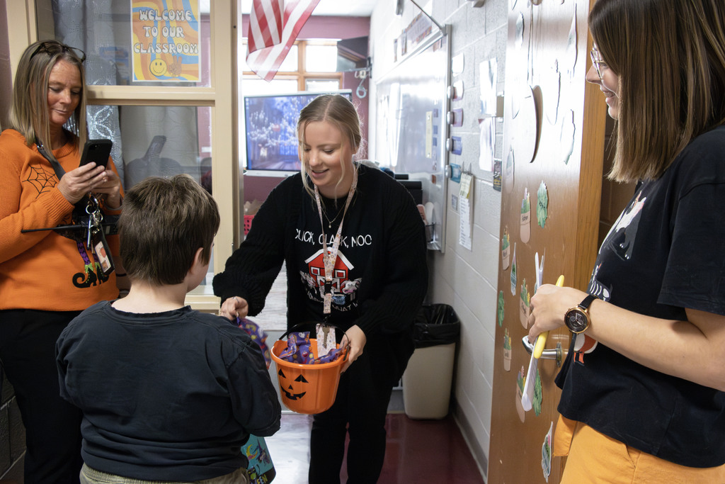 A teacher puts candy in the trick or treaters buckets