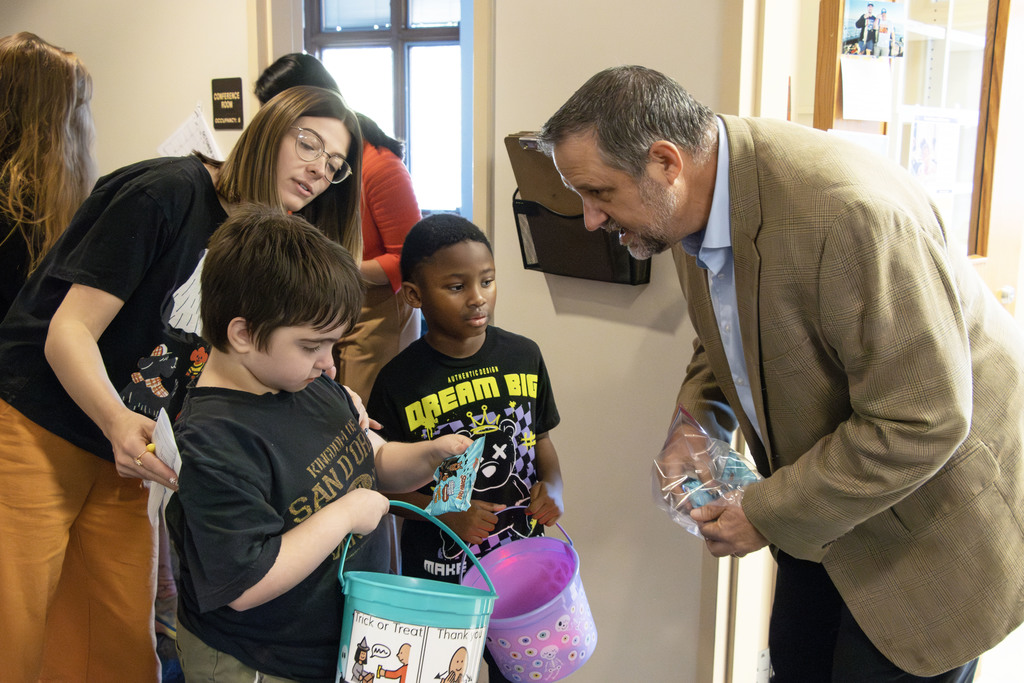 Mr. Gress puts candy in the trick or treaters buckets