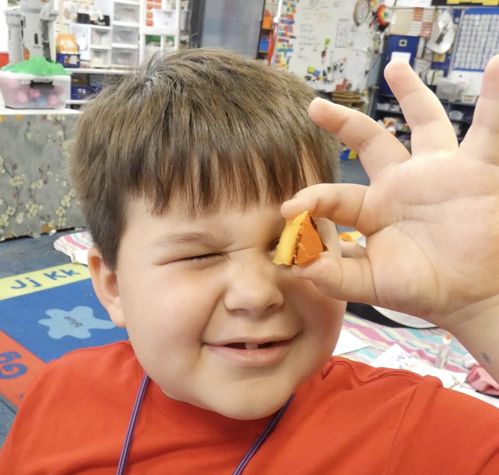 student holding up a piece of pumpkin to his eye