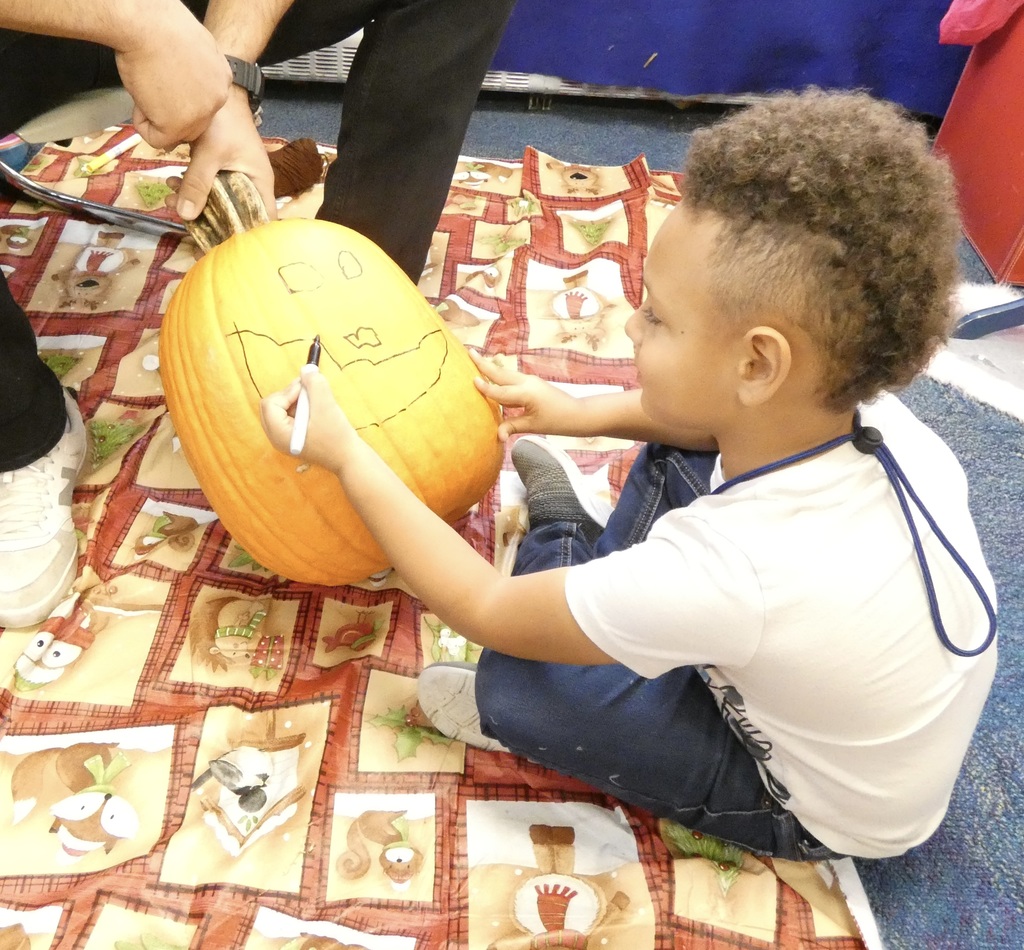 student drawing a face on pumpkins