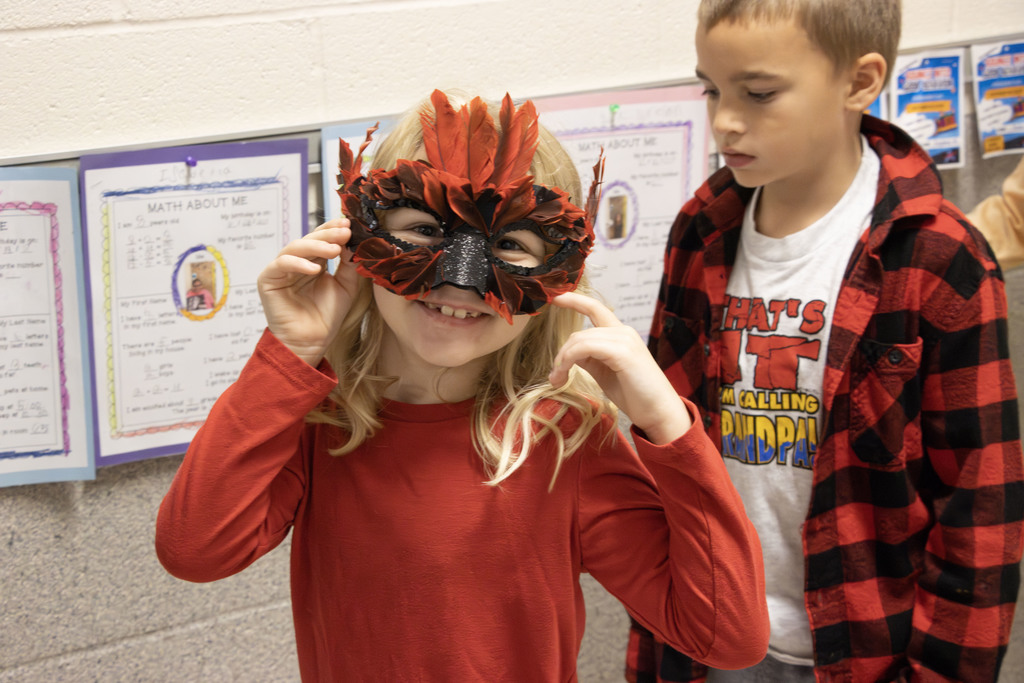 A student with a mardis gras mask smiles