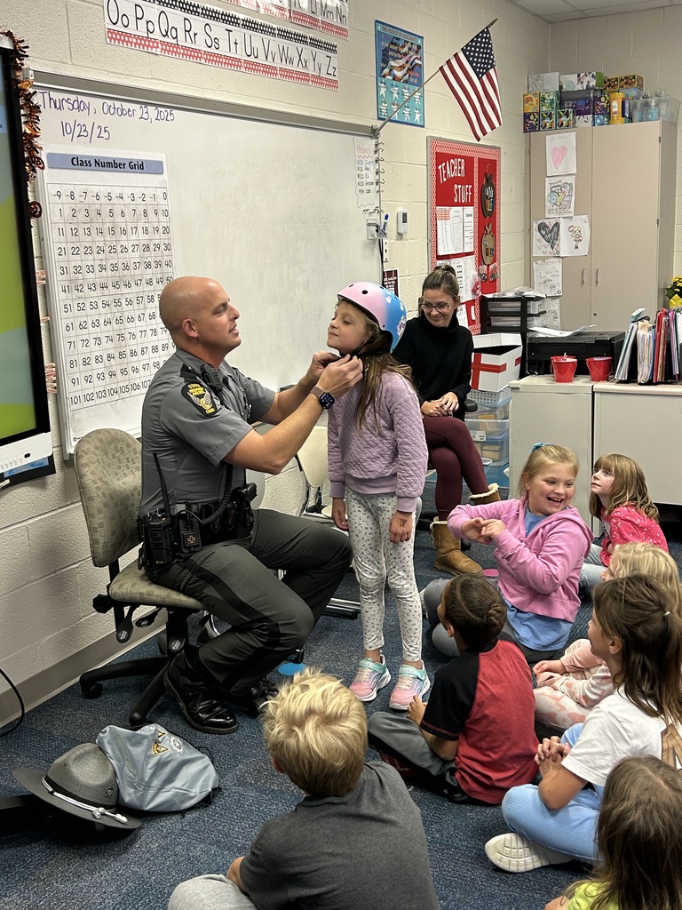 Trooper Shonk helping his daughter put on a bike helmet