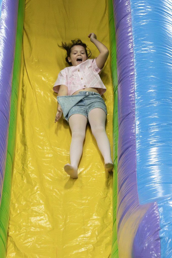 A student laughing as she slides down the slide