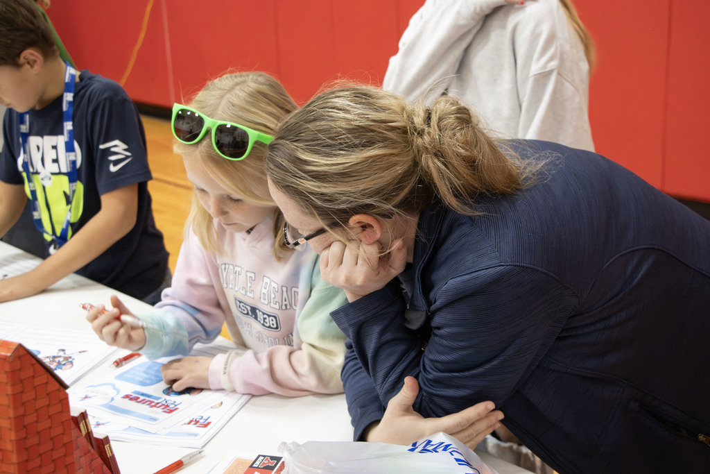 A parent helping her daughter fill out the form about what she wants to be when she grows up