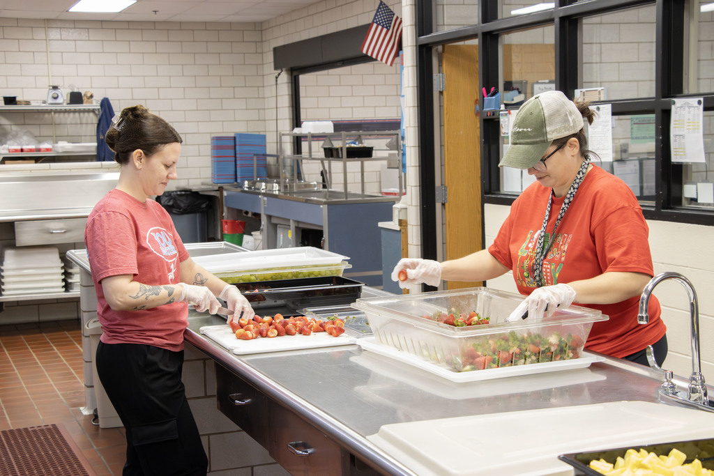 two staff members cutting fresh strawberries