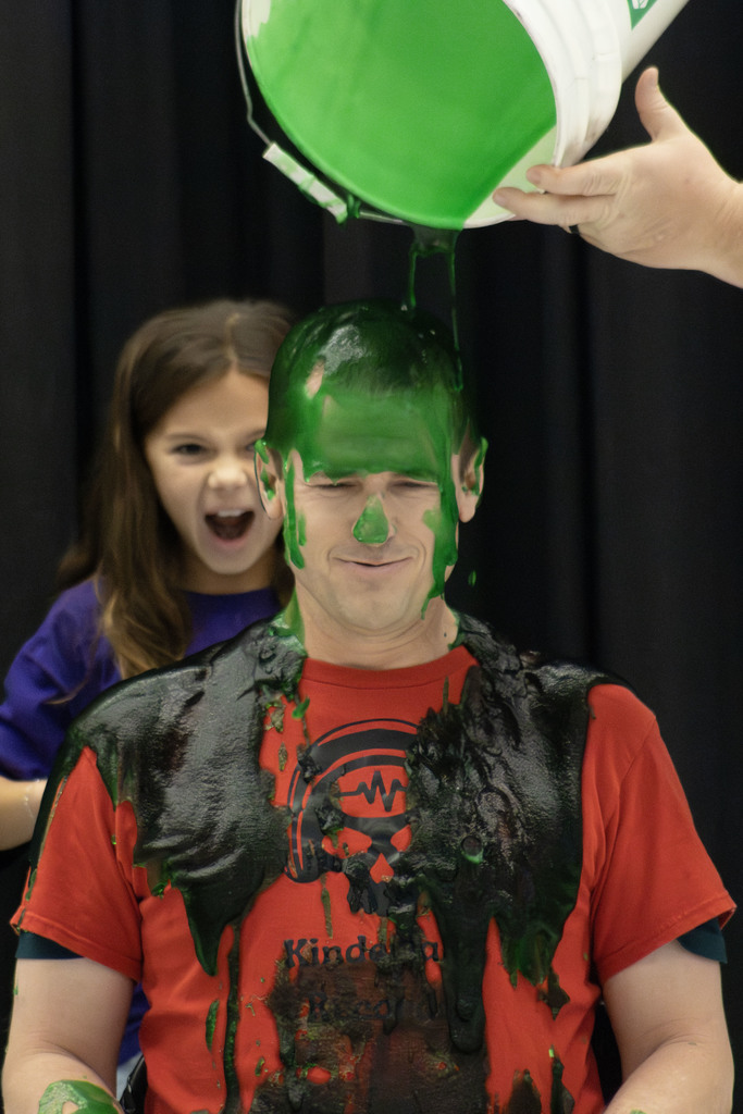 Justin Kinder having slimed dumped on his head while the student smiled behind him
