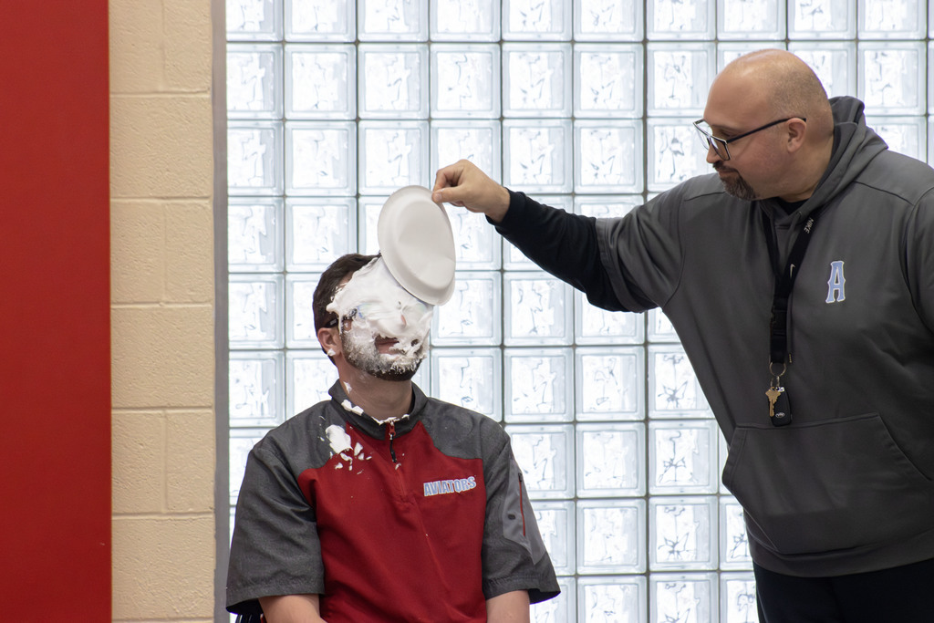 Mr. Angelica pulling a paper plate off of Mr. Logothetides face that a student left after pieing him