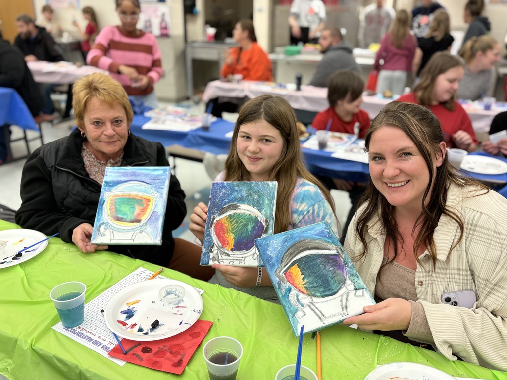 Families holding up their finished paintings