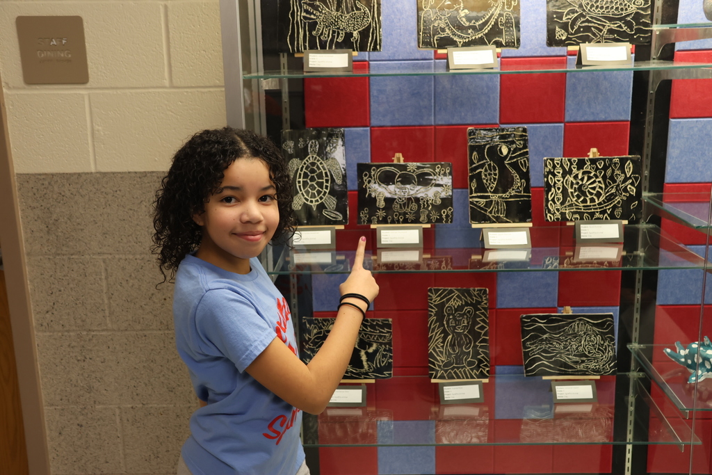 Student pointing at her artwork on display