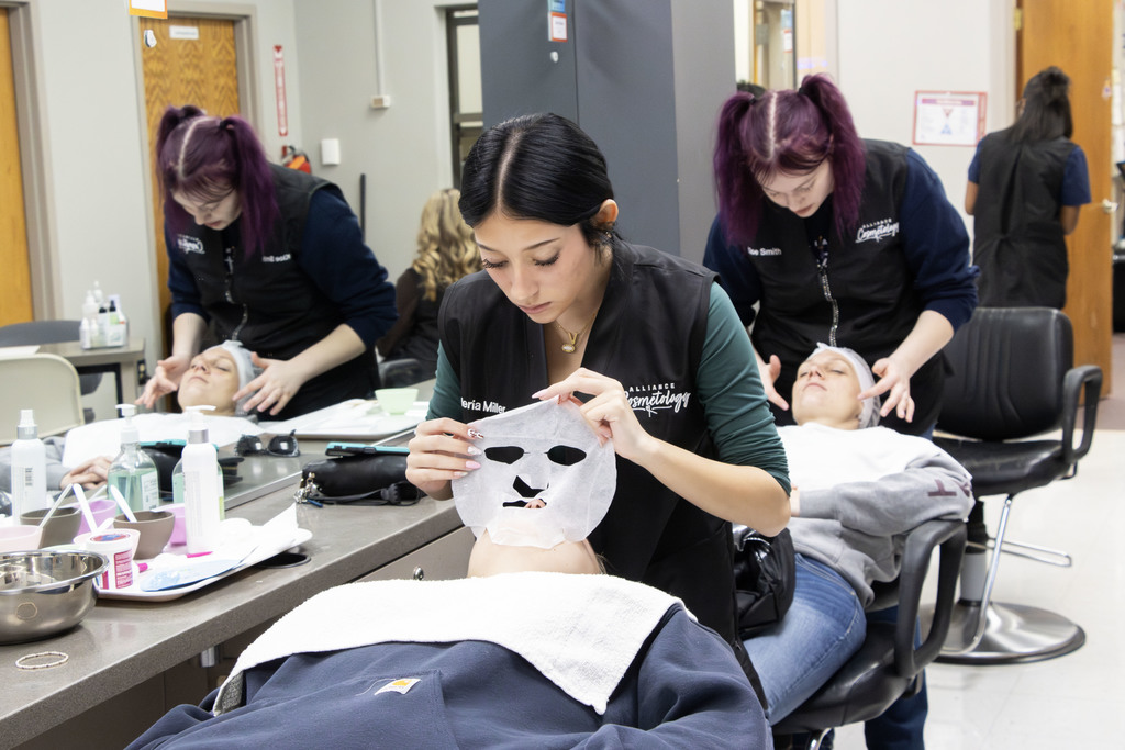 Student putting a mask on her client during a facial